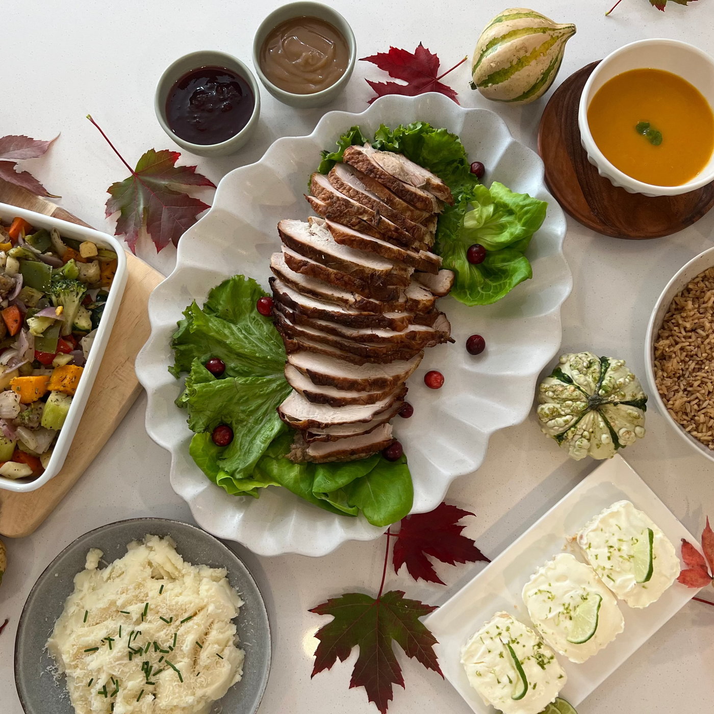 Thanksgiving turkey dinner including sliced turkey, salad, and side dishes on a table with autumn leaves in Burlington