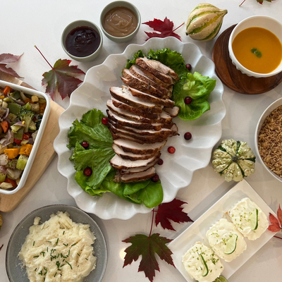 Thanksgiving turkey dinner including sliced turkey, salad, and side dishes on a table with autumn leaves in Burlington